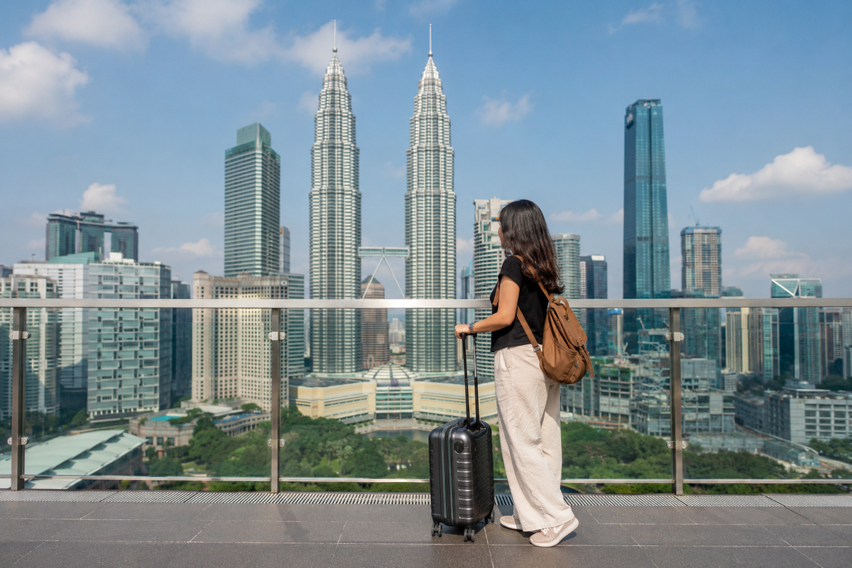 Traveler with suitcase overlooking Kuala Lumpur and Petronas Twin Towers