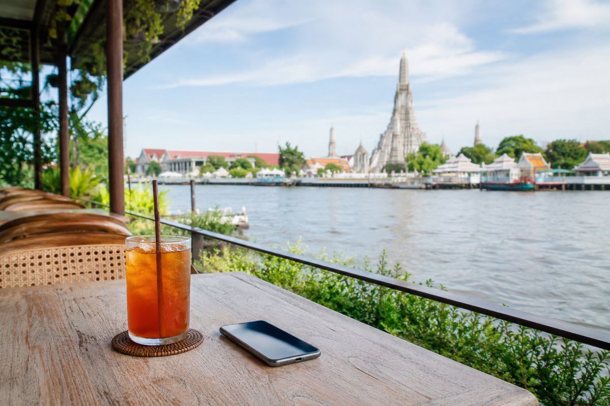 Smartphone on a Bangkok cafe table overlooking Wat Arun