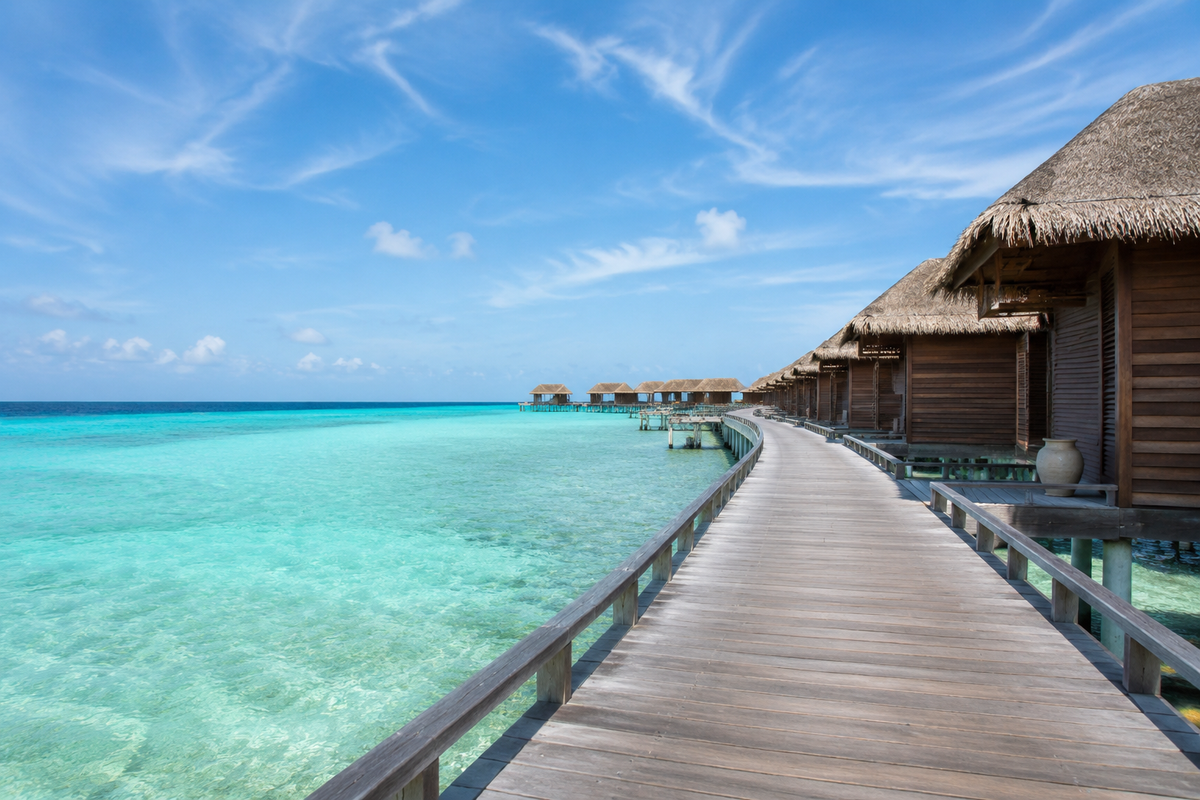 Wooden boardwalk leading to overwater villas above a Maldives lagoon