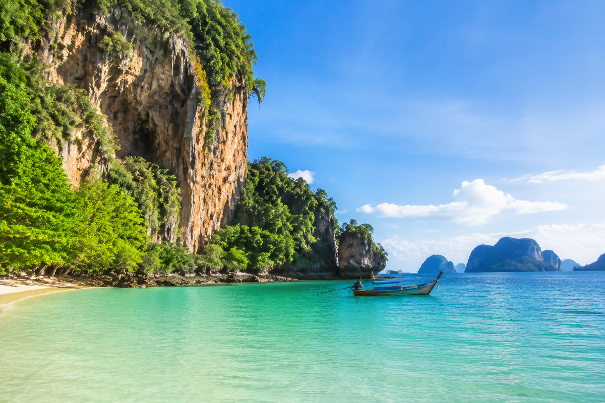 Illustration of a long-tail boat beside limestone cliffs on the Krabi coast.